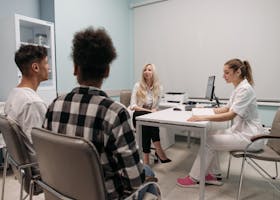 Doctors talking with patients during a medical appointment in a clinic office setting.